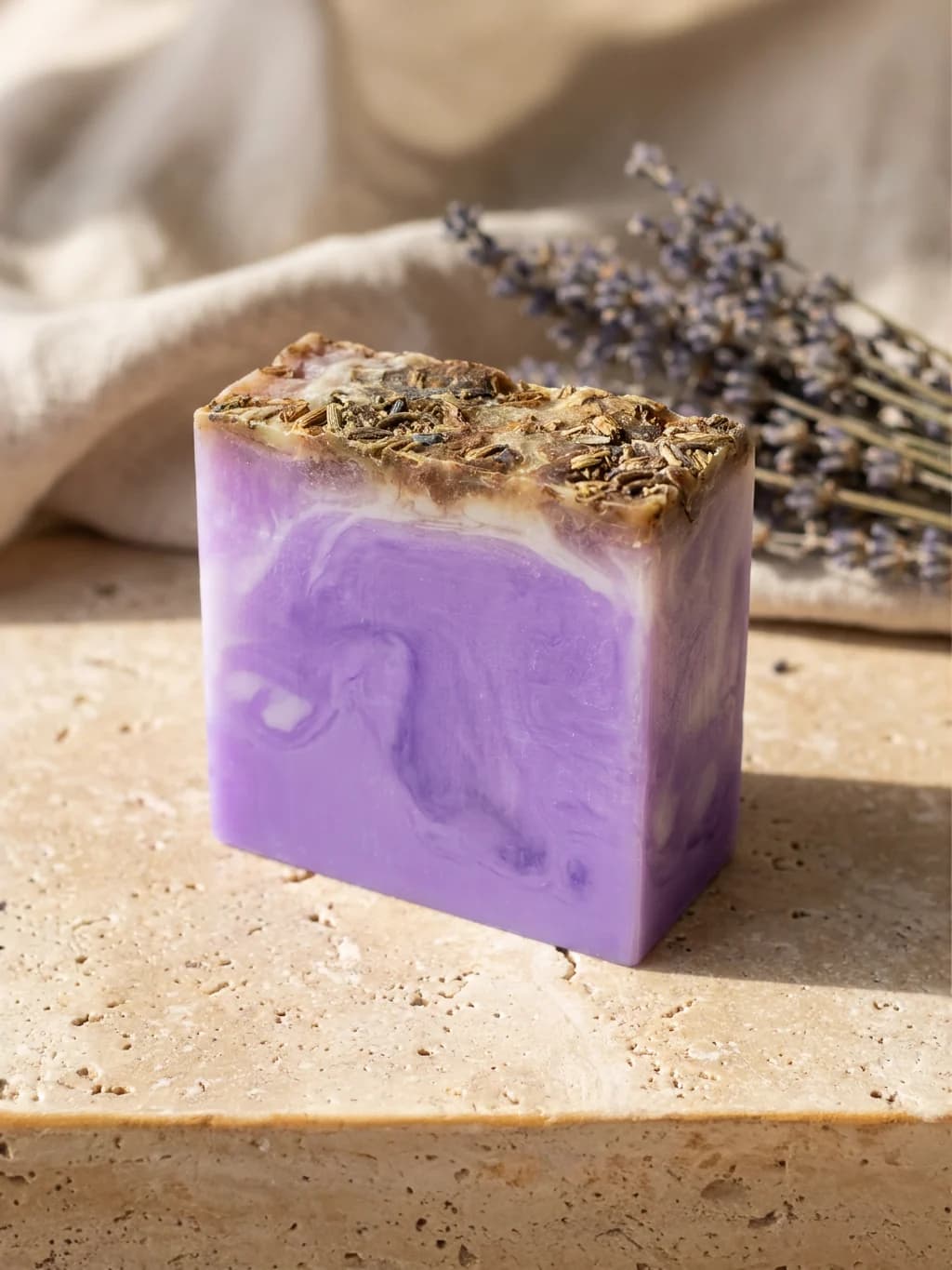 Savon parfumé à la lavande posé sur une pierre, entouré de brins de lavande